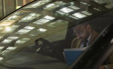Geschäftsmann überprüft Papierkram in der Nacht im Auto — Stockfoto