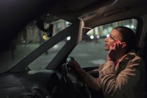 Mujer de negocios que aplica rímel en el coche por la noche - foto de stock