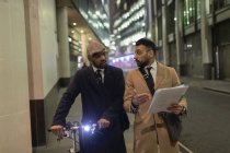 Uomini d'affari con biciclette e scartoffie che camminano sul marciapiede urbano — Foto stock