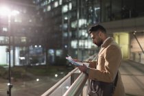 Бизнесмен рассматривает документы на городской пешеходный мост ночью — стоковое фото