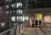 Geschäftsleute gehen nachts über städtische Fußgängerbrücke — Stockfoto
