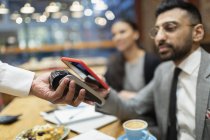 Бизнесмен в кафе платит смартфоном бесконтактной оплатой — стоковое фото
