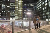 Geschäftsleute diskutieren nachts über Papierkram auf städtischer Fußgängerbrücke — Stockfoto