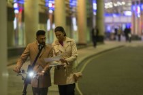 Geschäftsleute mit Fahrrad und Papierkram laufen nachts auf der Stadtstraße — Stockfoto