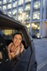 Усміхнена бізнес-леді розмовляє по смартфону в перевантаженому таксі вночі — стокове фото