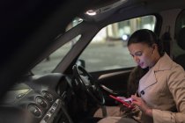 Geschäftsfrau nachts mit Smartphone im Auto — Stockfoto