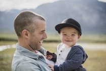 Father holding cute, happy baby son looking at camera — Stock Photo