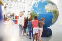 Teacher and students touching large globe in science center — Stock Photo