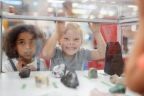 Silly girl making a face at rock exhibit display case in science center — Stock Photo