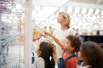 Teacher and curious students watching exhibit in science center — Stock Photo