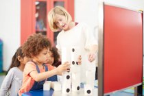 Lehrer und neugierige Schüler stapeln große Dominosteine im Science Center — Stockfoto