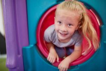 Retrato bonito, menina feliz jogando em slide tubo — Fotografia de Stock