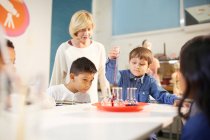 Teacher and students using pipette and beakers at interactive exhibit in science center — Stock Photo