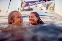 Heureux jeune couple adulte nageant près du catamaran dans l'océan — Photo de stock