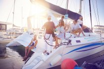 Amici che si rilassano sul catamarano in porto soleggiato — Foto stock