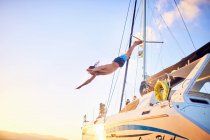 Jovem mergulhando fora catamarã — Fotografia de Stock
