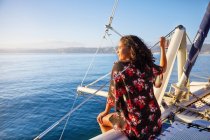 Молода жінка розслабляється на сонячному катамарані, дивлячись на блакитний океан — стокове фото
