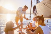 Amigos bebiendo champán en un catamarán soleado - foto de stock