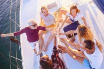 Вид сверху на друзей, тостующих шампанское на солнечной лодке — стоковое фото