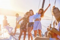 Mujeres juguetonas amigas bailando en un catamarán soleado - foto de stock