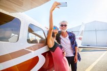Couple taking selfie with camera phone at small airplane — Stock Photo