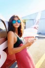 Портрет впевнена молода жінка з смартфоном, що спирається на маленький літак — стокове фото