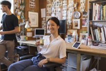 Retrato sonriente, confiada empresaria creativa bebiendo té en la oficina - foto de stock