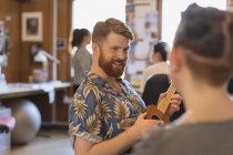 Улыбающийся креативный бизнесмен играет на укулеле в офисе — стоковое фото