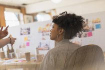 Креативна жінка-дизайнерка слухає колегу в офісі — стокове фото