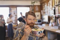 Creative businessman eating soup in office — Stock Photo