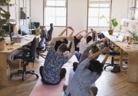 Gente creativa de negocios estirándose, practicando yoga en la oficina - foto de stock