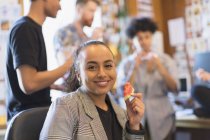 Портрет улыбающейся творческой предпринимательницы, кушающей арбуз в офисе — стоковое фото