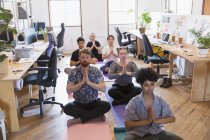 Creative business people meditating in office — Stock Photo