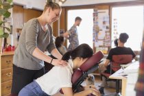 Creative businesswoman receiving massage from masseuse in office — Stock Photo