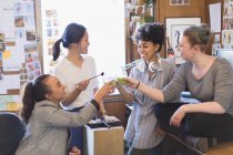 Designers femininos criativos brindando smoothies verdes no escritório — Fotografia de Stock
