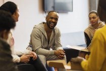 Sonriente mentor masculino hablando con adolescentes en la organización juvenil - foto de stock