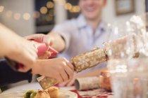 Family pulling Christmas crackers at dinner table — Stock Photo
