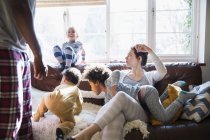 Multi-étnica jovem família em pijama jogando na sala de estar ensolarada — Fotografia de Stock