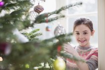 Portrait smiling girl decorating Christmas tree — Stock Photo