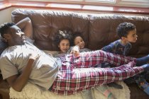 Portrait enfants heureux et insouciants en pyjama câlins avec le père sur le canapé du salon — Photo de stock