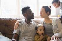 Affettuosa famiglia multietnica giovane sul divano del soggiorno — Foto stock