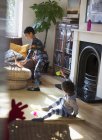 Hermanos en pijama jugando con juguetes en salón - foto de stock
