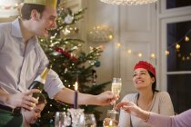 Happy man serving champagne at candlelight Christmas dinner — Stock Photo
