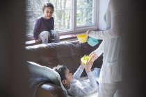 Mother giving snacks to children in living room — Stock Photo