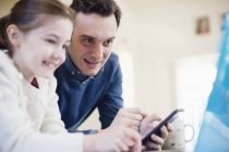 Pai com telefone inteligente usando laptop com filha — Fotografia de Stock