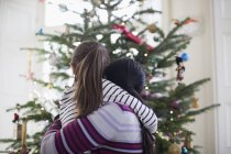 Affettuosi mamma e figlia che si abbracciano davanti all'albero di Natale — Foto stock