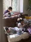 Padre e hijos relajándose, abrazándose en el sofá de la sala de estar - foto de stock