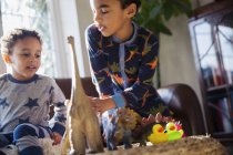 Brüder im Pyjama spielen mit Dinosaurier-Spielzeug — Stockfoto