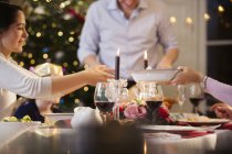 Family passing food, enjoying candlelight Christmas dinner — Stock Photo