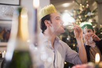 Fille regardant père heureux en couronne de papier boire du champagne au dîner de Noël — Photo de stock